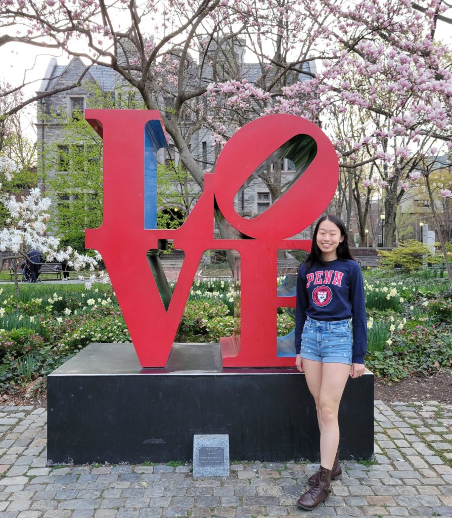 Annabelle Jin stands next to a sculpture made of the word love